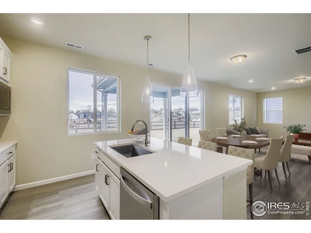 a kitchen with center island a sink dishwasher a dining table and chairs with wooden floor