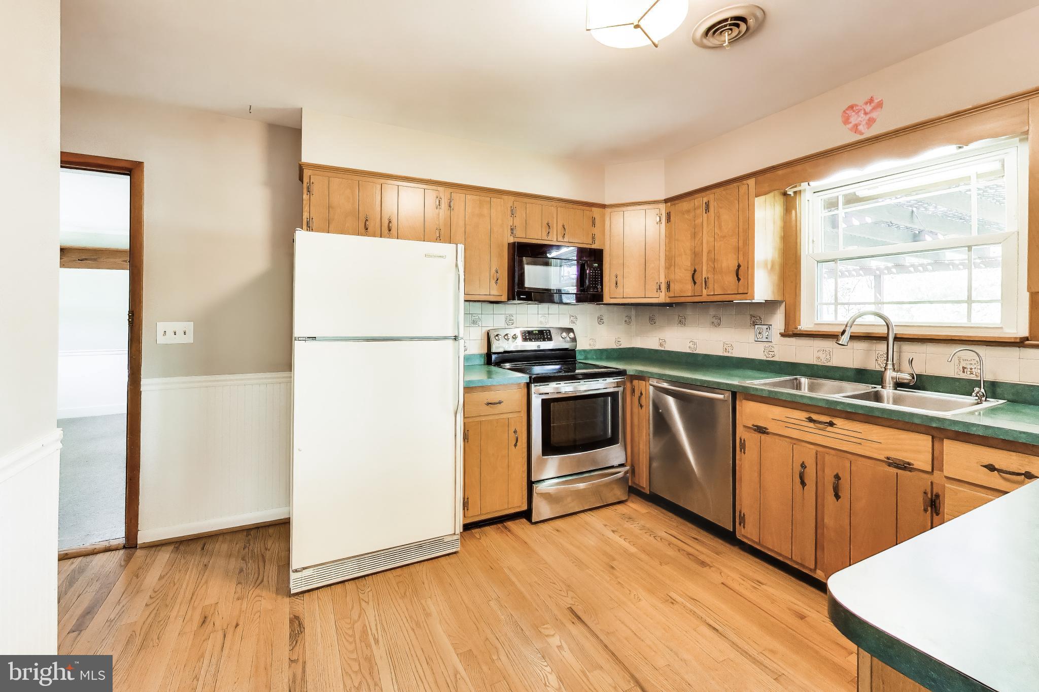 3904 Overlook Lane Monrovia, MD 21770 - Photo 12 of 54 a kitchen with granite countertop a refrigerator a sink dishwasher a stove top oven a refrigerator with grey cabinets and wooden floor