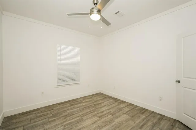 an empty room with wooden floor fan and windows