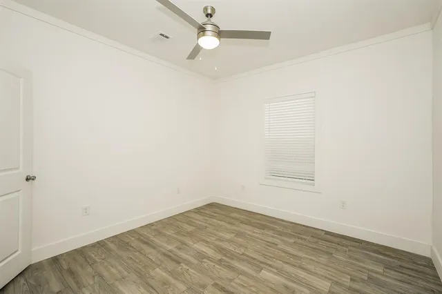 an empty room with wooden floor and fan