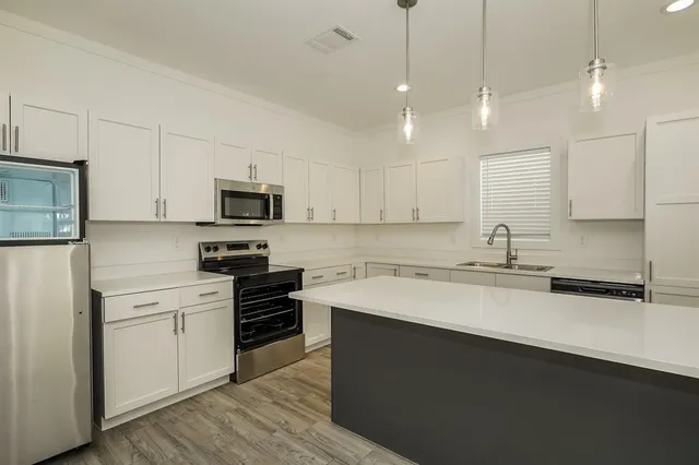 a kitchen with a sink stainless steel appliances and white cabinets