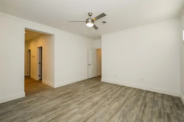 an empty room with wooden floor and a ceiling fan