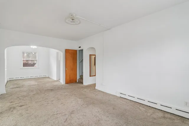 an empty room with windows and refrigerator