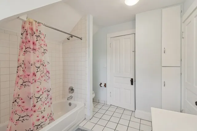 an empty room with a chandelier fan and closet area