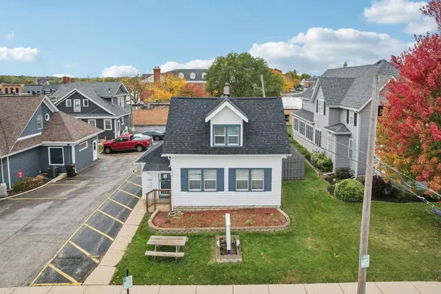 a view of a white house next to a yard with big trees