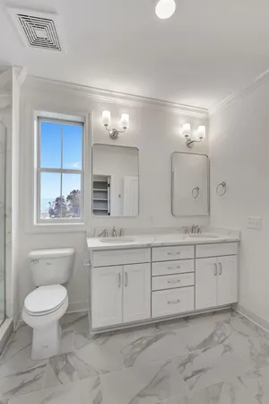 a bathroom with a toilet a sink a mirror and a window
