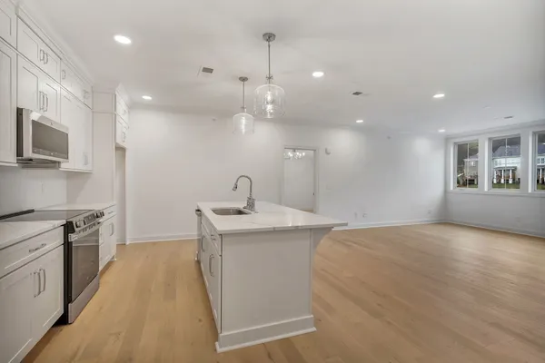 a kitchen with stainless steel appliances granite countertop a sink a stove and a wooden floors