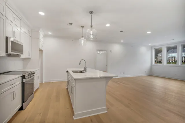 a kitchen with stainless steel appliances granite countertop a sink a stove and a wooden floors