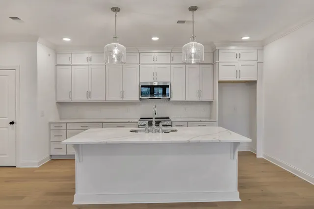 a kitchen with kitchen island white cabinets and stainless steel appliances