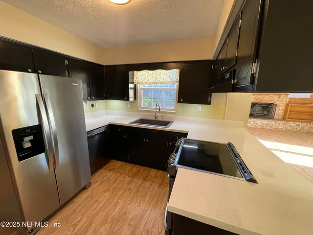 a kitchen with granite countertop a refrigerator a sink and dishwasher