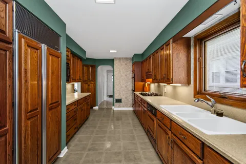 a large kitchen with kitchen island granite countertop a sink and dishwasher wooden cabinets with a large window