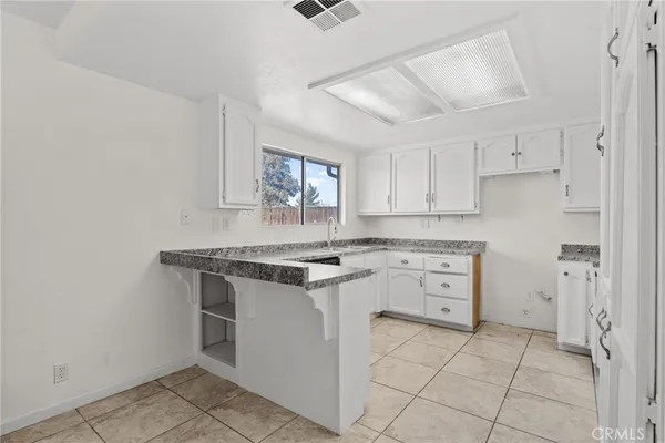 a kitchen with granite countertop stainless steel appliances white cabinets granite counter tops and a wooden floors