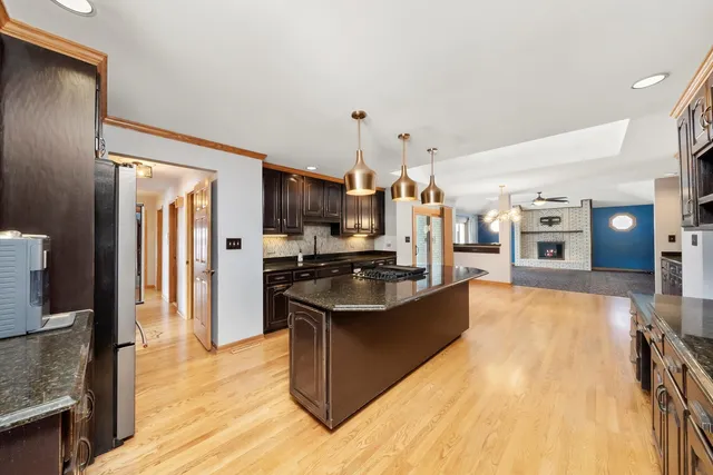 a kitchen with stainless steel appliances kitchen island granite countertop a stove refrigerator and cabinets