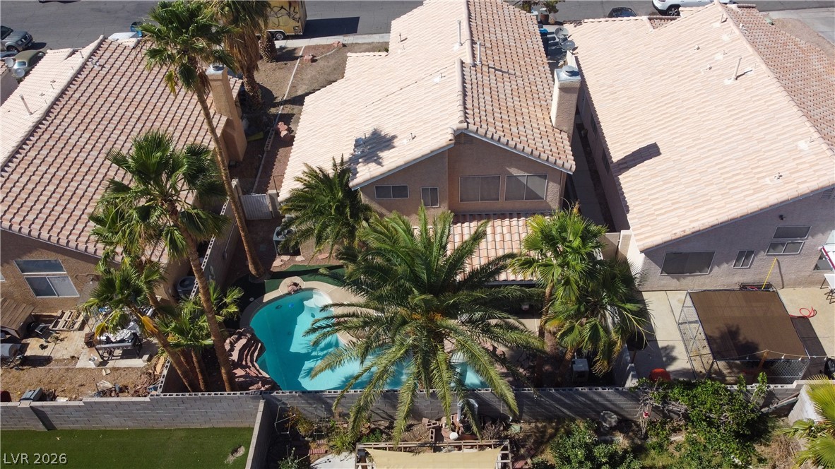 6429 Winding Ridge Las Vegas, NV 89156 - Photo 4 of 16 An aerial perspective reveals a private pool nestled among palms, highlighting the home's tiled roof and secluded backyard.