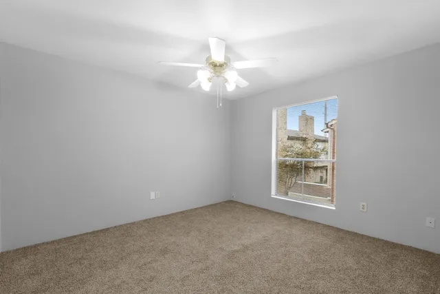 an empty room with windows and fan