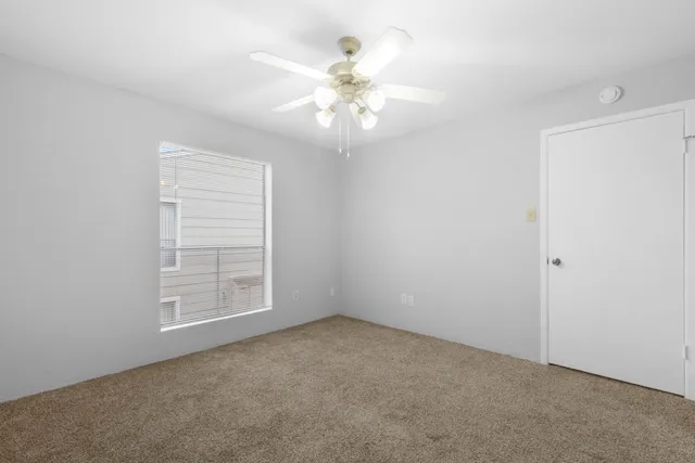 an empty room with windows and chandelier fan