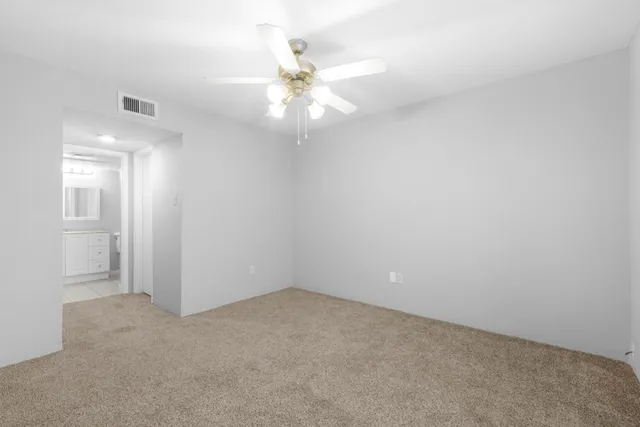 an empty room with a chandelier fan and windows