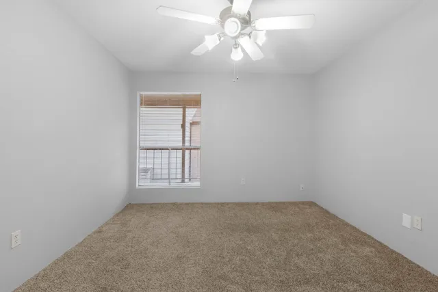 an empty room with a window and a fan