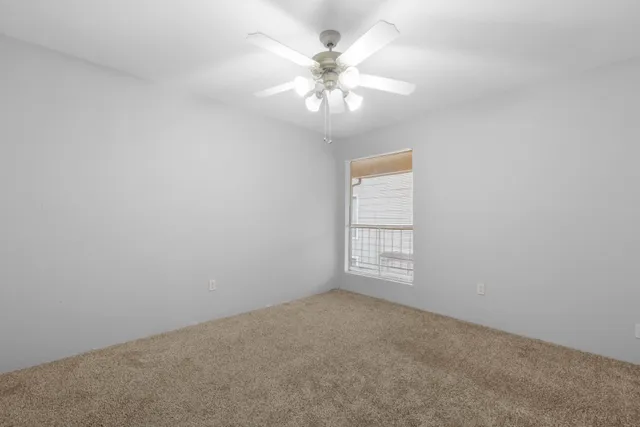 an empty room with windows and chandelier fan