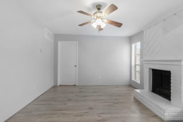 an empty room with a fireplace and a ceiling fan