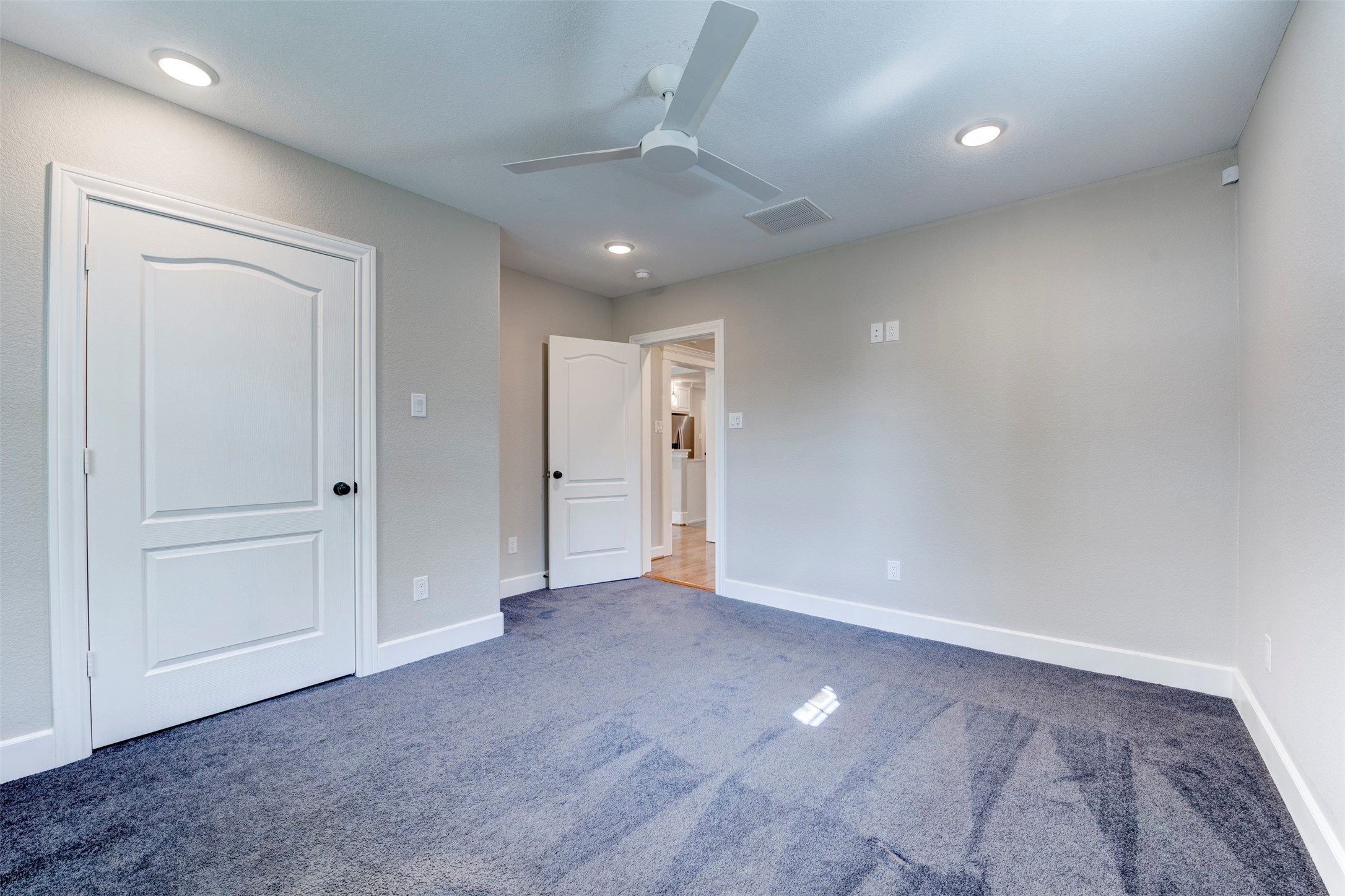 109 Dresden Street Houston, TX 77012 - Photo 32 of 43 This room features neutral walls, a ceiling fan, recessed lighting, and plush carpeting. It has a doorway leading to another space and a closed door for additional privacy or storage.