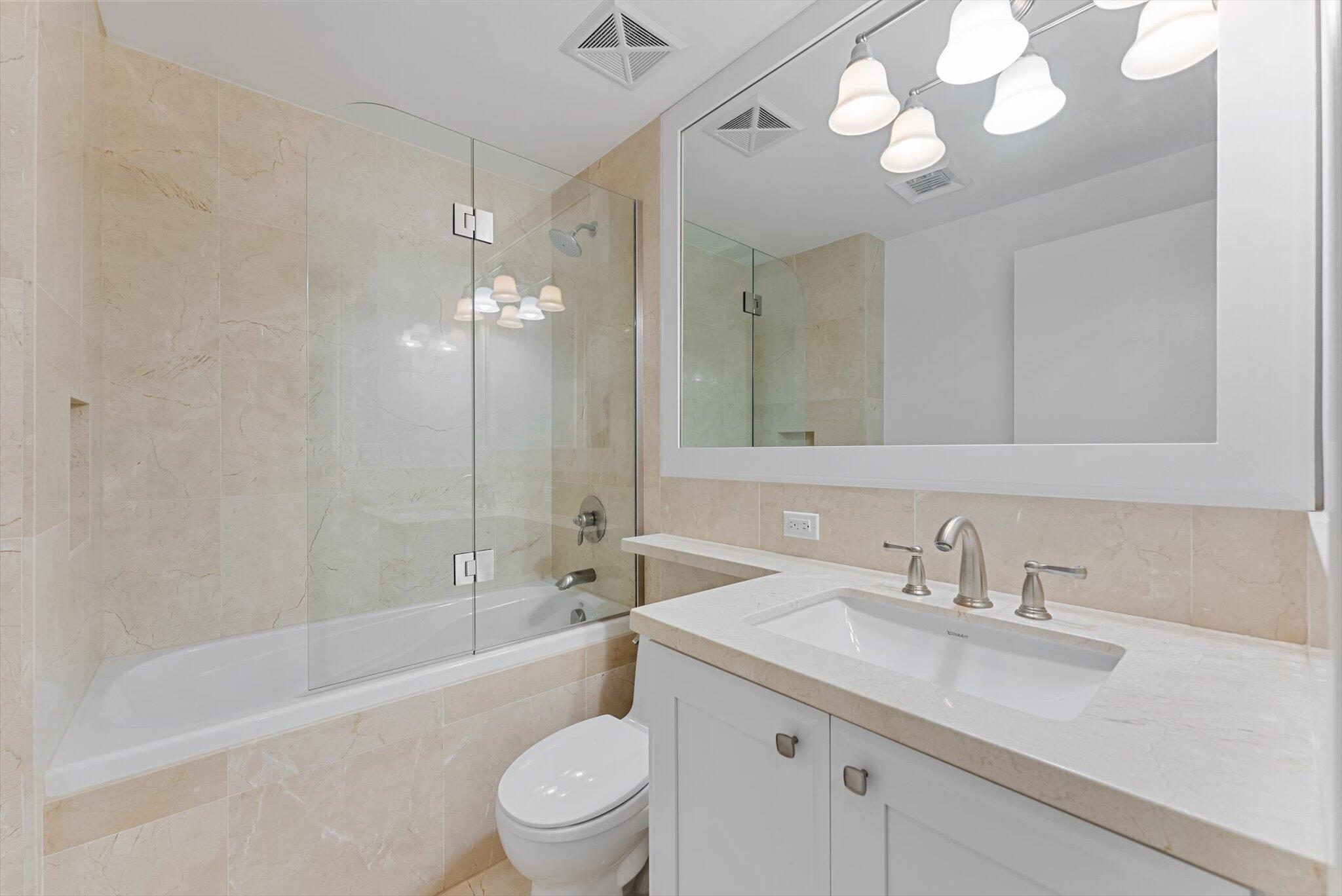 455 East Palmetto Park Road, Unit 6E Boca Raton, FL 33432 - Photo 18 of 28 a bathroom with a sink a toilet a mirror a bathtub and shower