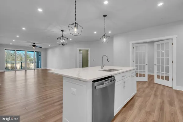 a large kitchen with kitchen island a stove a refrigerator a sink and a oven with wooden floor