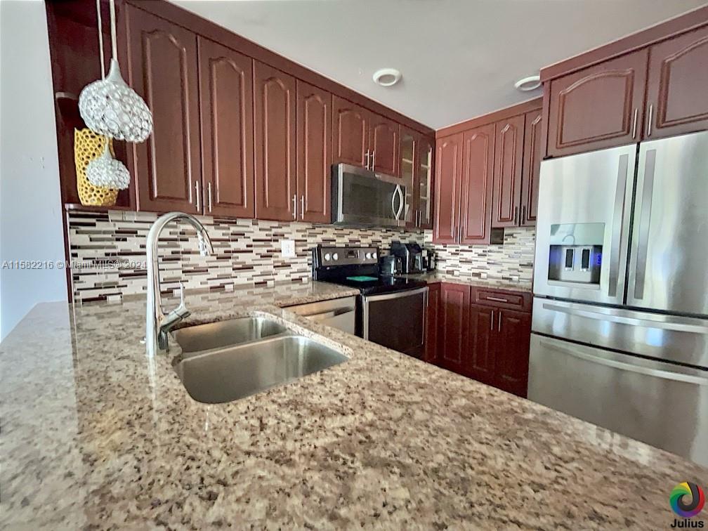 a kitchen with kitchen island granite countertop a sink stainless steel appliances and cabinets