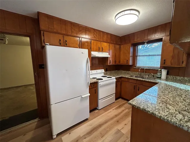 a kitchen that has a lot of cabinets a stove and a wooden floor