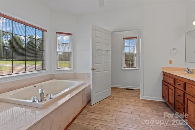 a spacious bathroom with a tub sink and mirror