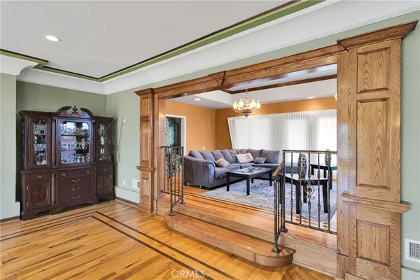 a living room with stainless steel appliances kitchen island granite countertop a refrigerator a sink a dining table and chairs with wooden floor