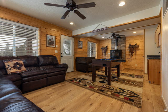 1505 West Elk Ridge Drive Alton, UT 84710 - Photo 29 of 53 Living room with a textured ceiling, ceiling fan, a wood stove, recessed lighting, and wood walls