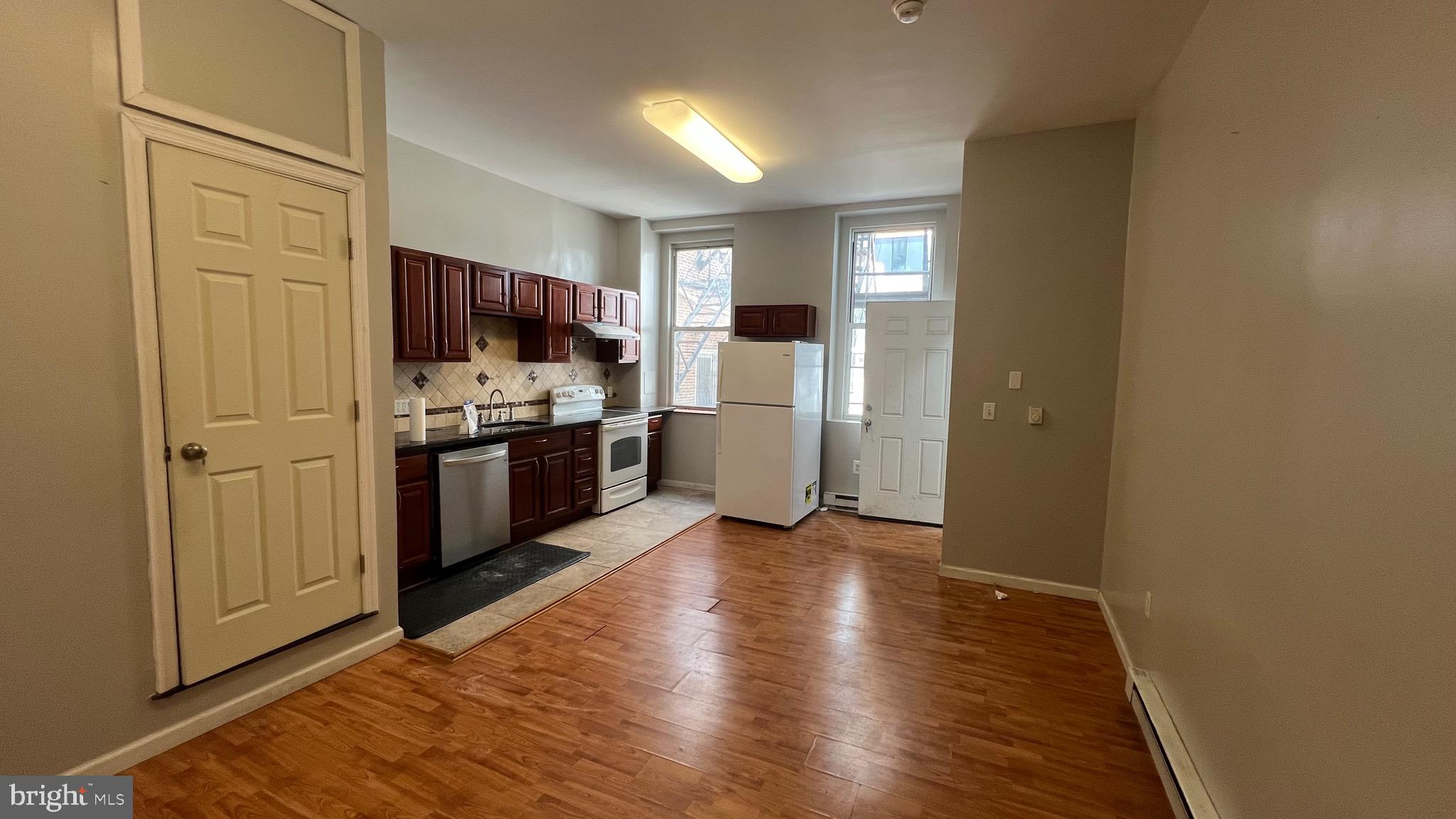 1115 Walnut Street, Unit 2F Philadelphia, PA 19107 - Photo 11 of 14 a view of open kitchen with a sink refrigerator and wooden floor