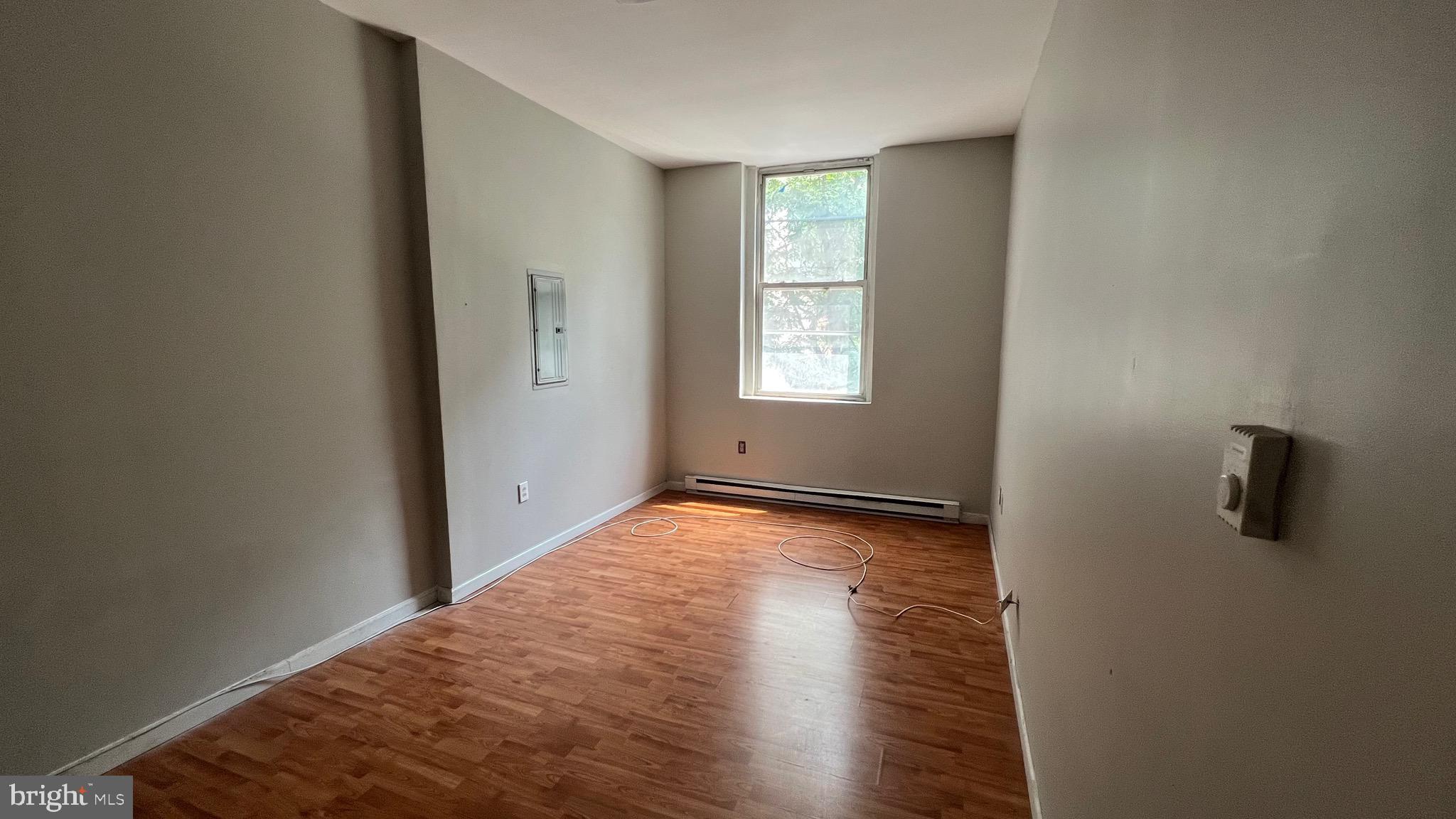 1115 Walnut Street, Unit 2F Philadelphia, PA 19107 - Photo 6 of 14 a view of an empty room with wooden floor and a window