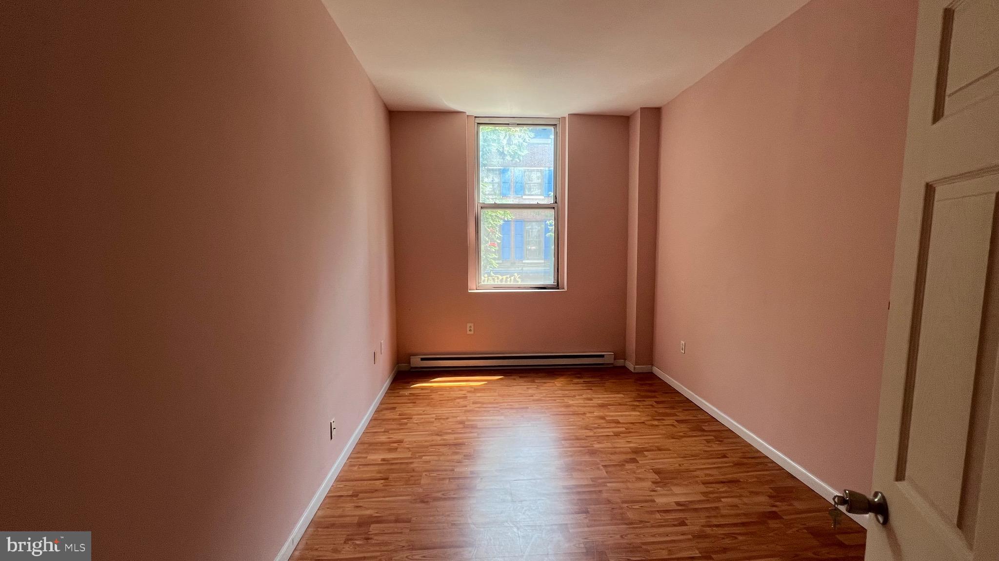 1115 Walnut Street, Unit 2F Philadelphia, PA 19107 - Photo 8 of 14 an empty room with wooden floor and windows
