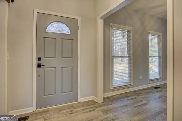 an empty room with wooden floor closet and windows