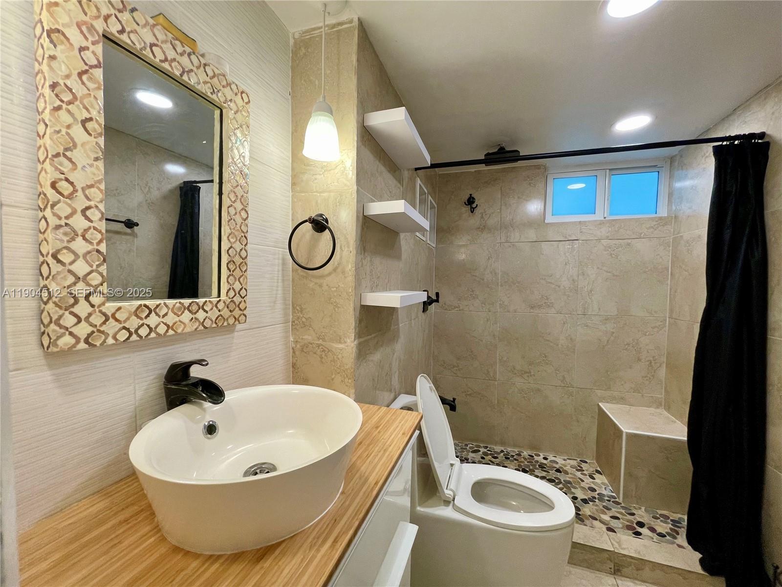 1670 Bay Road, Unit 2B Miami Beach, FL 33139 - Photo 7 of 15 a bathroom with a sink a toilet and a mirror