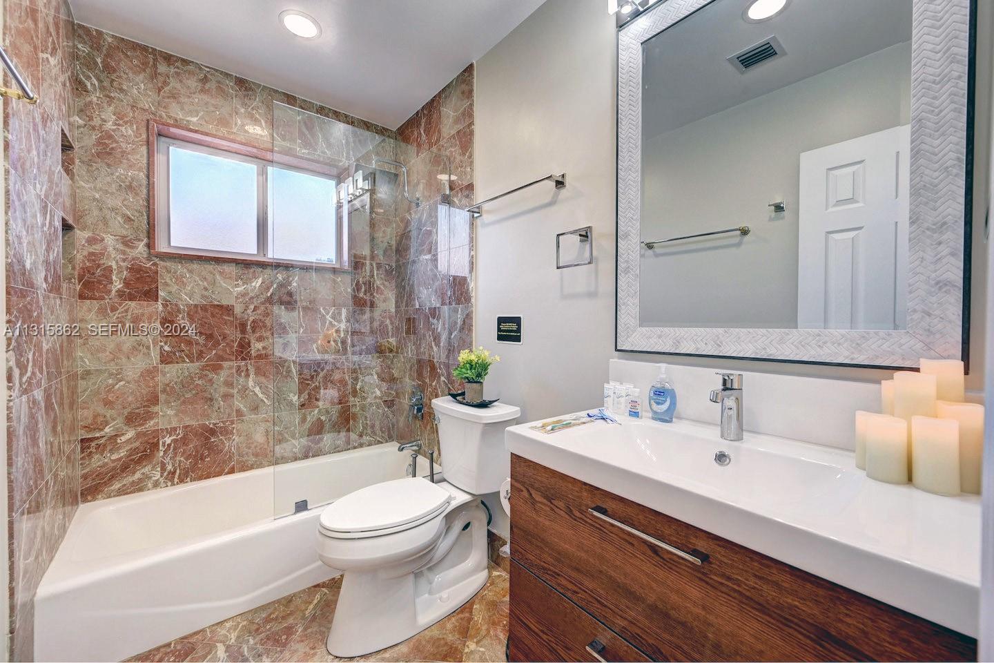 1307 Rodman Street Hollywood, FL 33019 - Photo 33 of 38 a bathroom with a sink a toilet a mirror a bathtub and shower