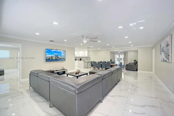 a living room with couches and kitchen view with wooden floor