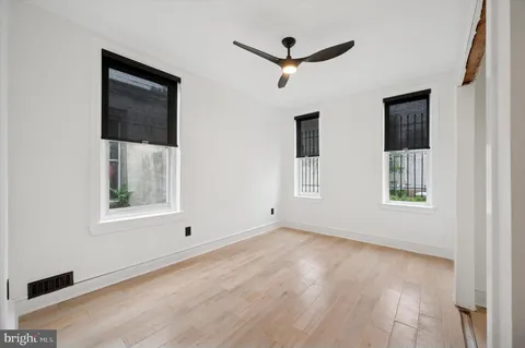 a view of an empty room with a window and wooden floor