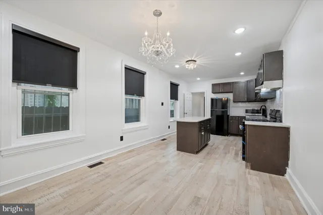 a large kitchen with kitchen island a large counter top space stainless steel appliances a window and a chandelier