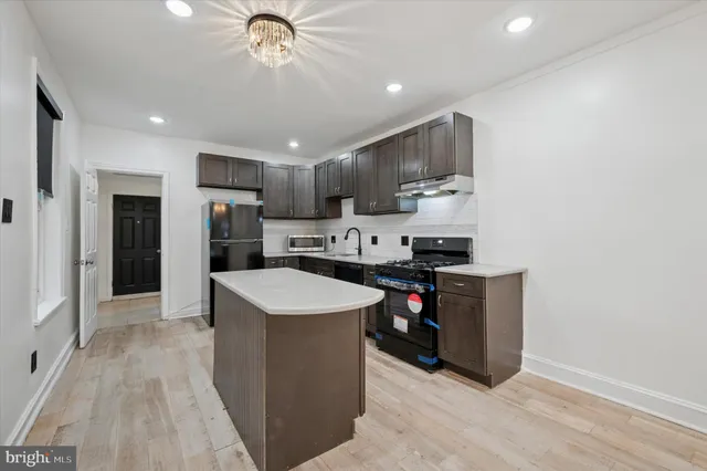 a kitchen with stainless steel appliances a stove a refrigerator a sink dishwasher and a oven with wooden floor