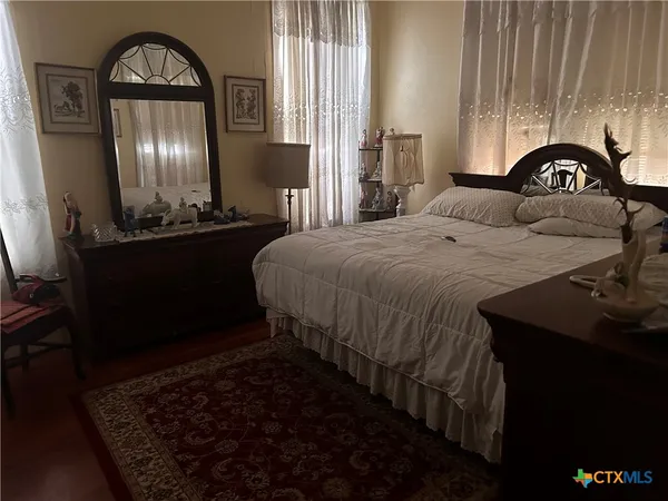 a bedroom with a bed and a dresser with mirror on dresser