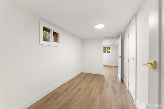 a view of a hallway with wooden floor and a bathroom