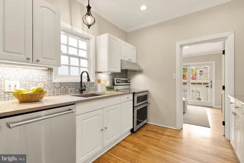 a kitchen with granite countertop a sink cabinets stainless steel appliances and a window