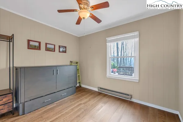a view of an empty room with window and wooden floor