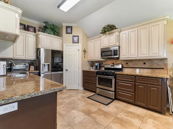 a kitchen with granite countertop a refrigerator stove top oven and sink