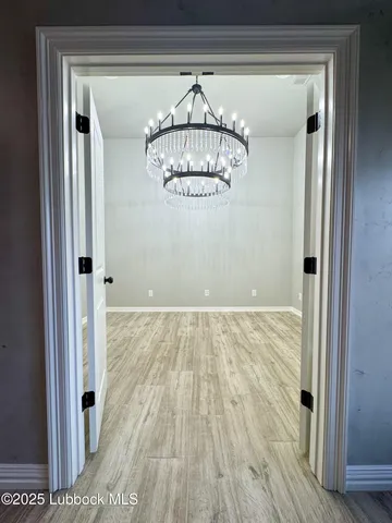 a view of a hallway with wooden floor and chandelier