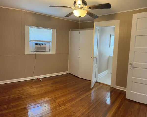 an empty room with wooden floor fan and windows