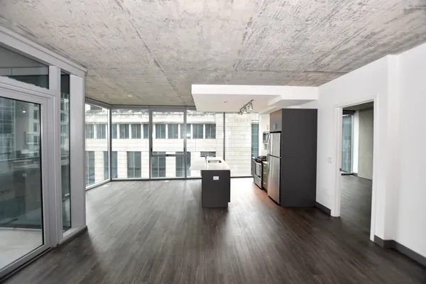a living room with stainless steel appliances kitchen island hardwood floor and a large window